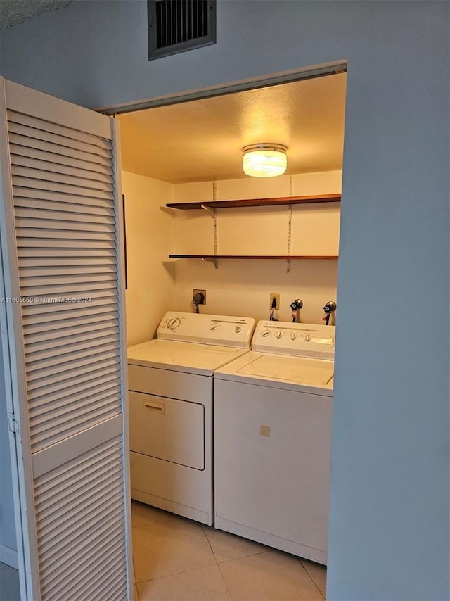 washroom featuring washing machine and clothes dryer, visible vents, laundry area, and light tile patterned floors