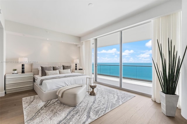 bedroom featuring a water view, access to outside, and light wood-type flooring