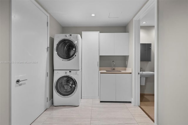 clothes washing area featuring stacked washer / drying machine, sink, and light tile patterned floors