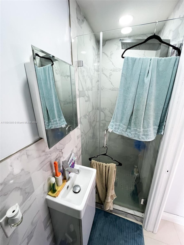 bathroom with a shower with door, tile flooring, and sink