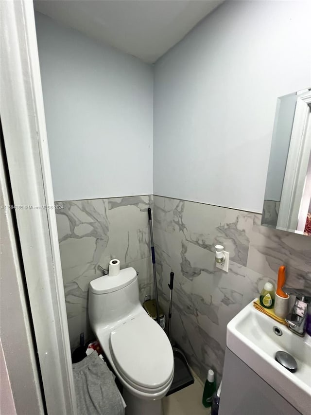 bathroom featuring tile walls, toilet, vanity, and tasteful backsplash