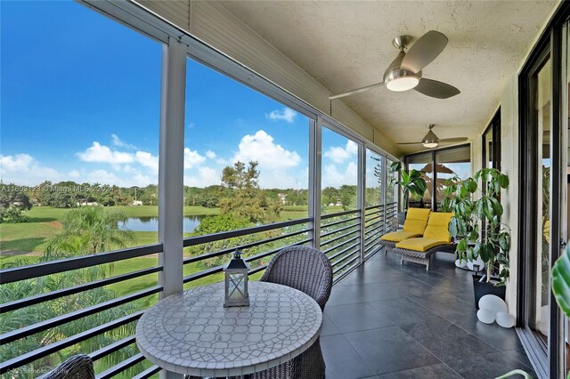 sunroom / solarium with a water view and ceiling fan