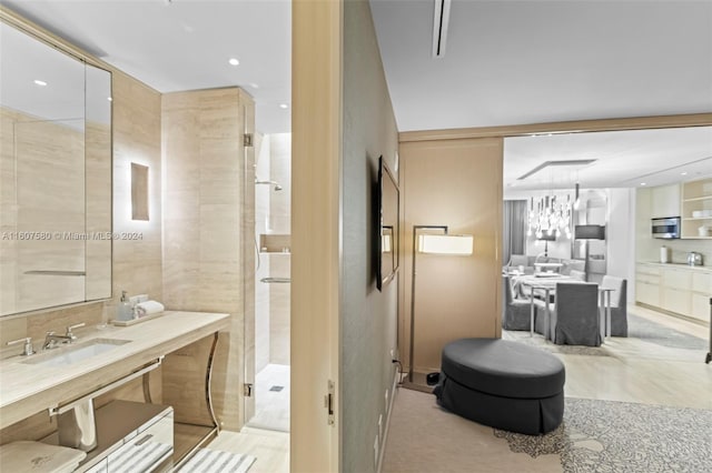 bathroom featuring vanity, a chandelier, a shower with shower door, and tile walls