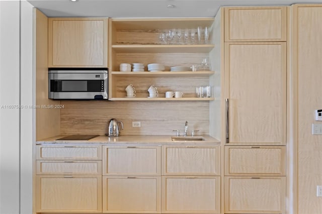 bar with black electric stovetop, sink, and light brown cabinetry