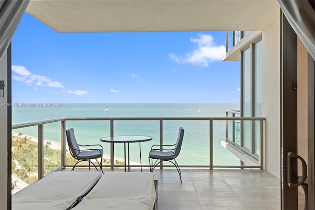 balcony with a water view and a view of the beach