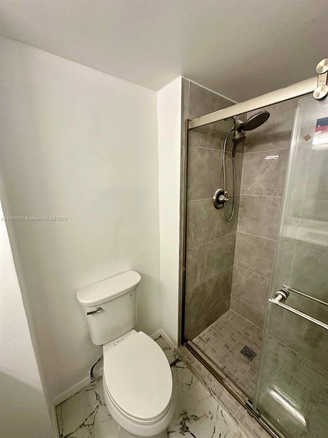 bathroom with a shower with shower door and toilet