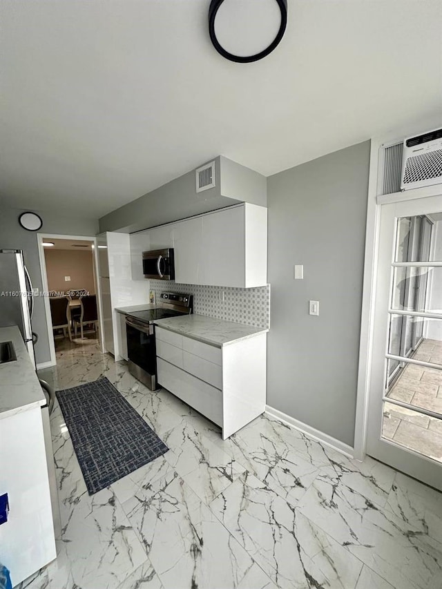 kitchen with white cabinetry, stainless steel appliances, and tasteful backsplash