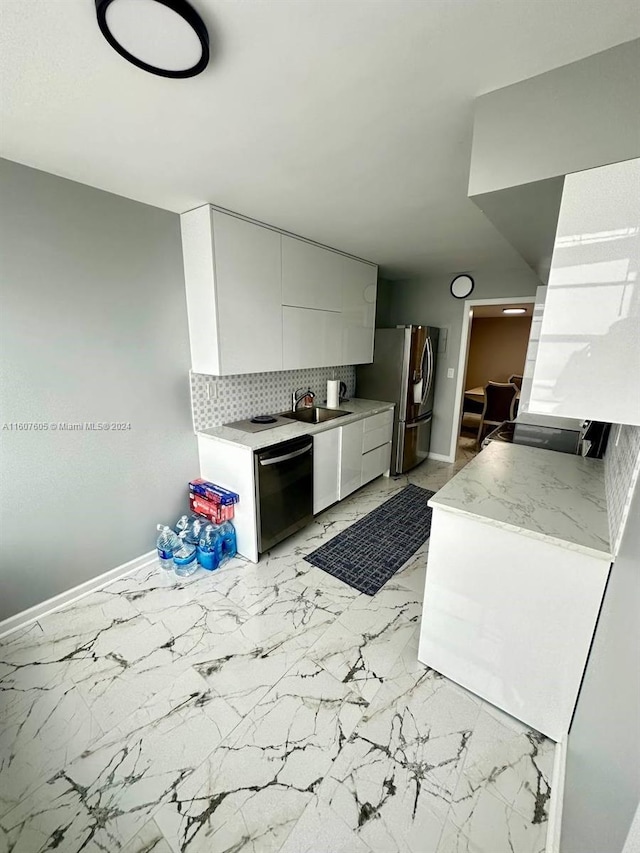 kitchen featuring stainless steel refrigerator, tasteful backsplash, white cabinetry, dishwasher, and sink