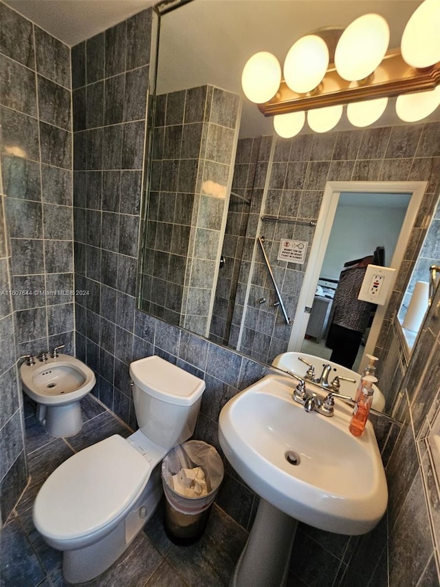 bathroom with tile walls, tile patterned floors, toilet, and a bidet