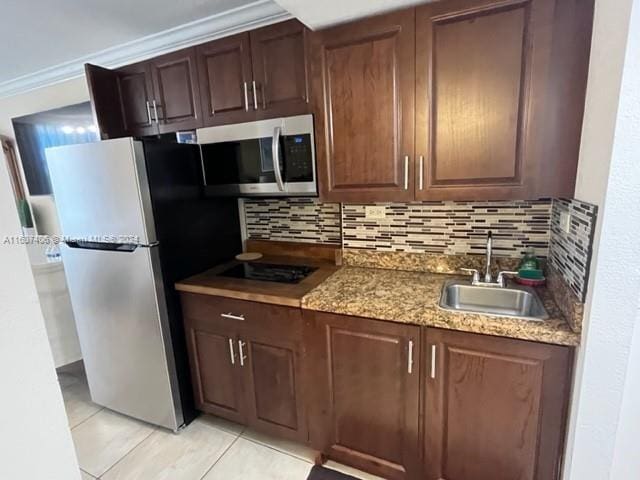 kitchen featuring appliances with stainless steel finishes, light stone counters, sink, light tile patterned flooring, and decorative backsplash