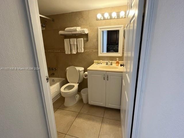 full bathroom with vanity, tile patterned flooring, tile walls, toilet, and tiled shower / bath