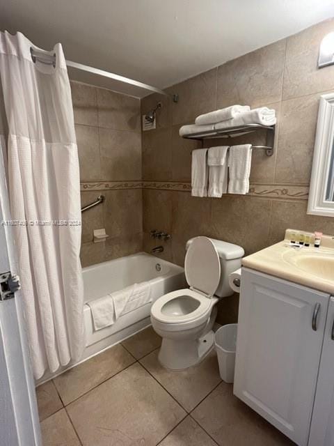 full bathroom with toilet, tile patterned floors, vanity, shower / bath combo with shower curtain, and tile walls