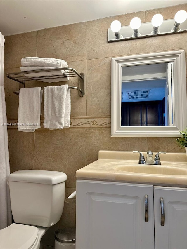 bathroom featuring vanity, toilet, and tile walls