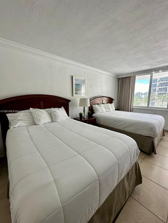 tiled bedroom with ornamental molding and a textured ceiling