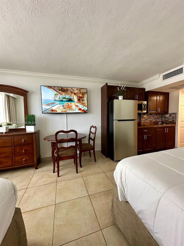 bedroom featuring stainless steel fridge, light tile patterned floors, a textured ceiling, and ornamental molding