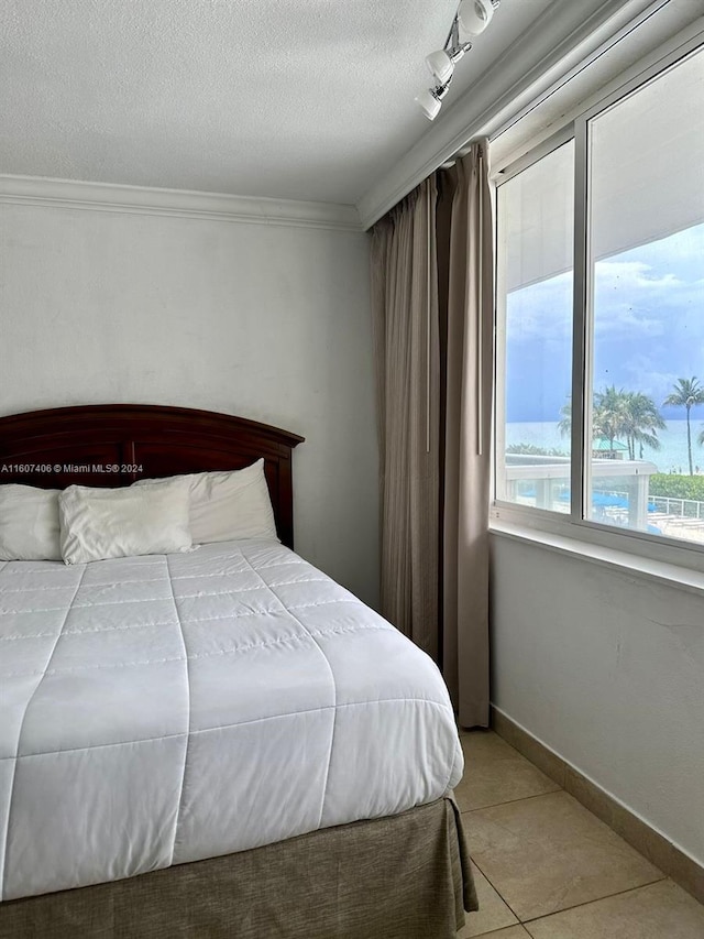 bedroom featuring ornamental molding, a textured ceiling, and tile patterned floors