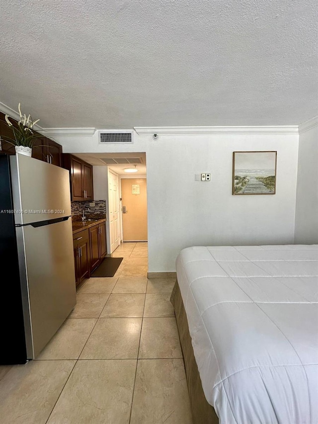 tiled bedroom with crown molding, stainless steel fridge, and a textured ceiling