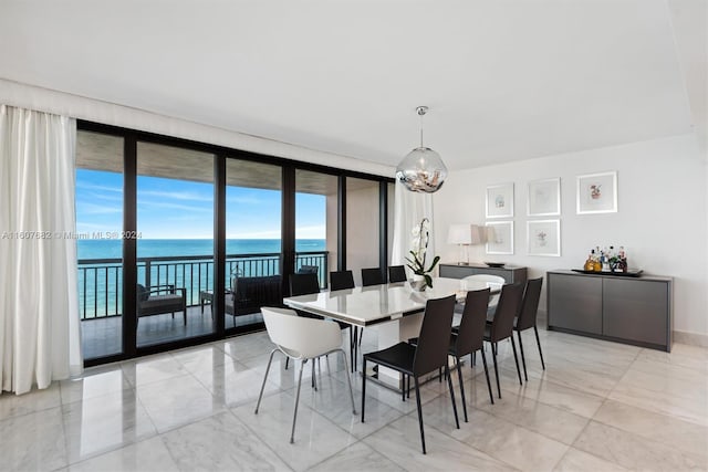 dining area featuring a water view, light tile floors, and a wall of windows