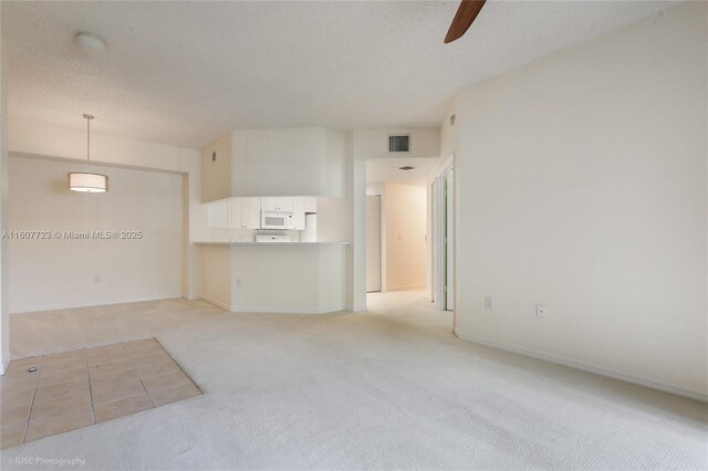 empty room featuring a textured ceiling, light colored carpet, and ceiling fan