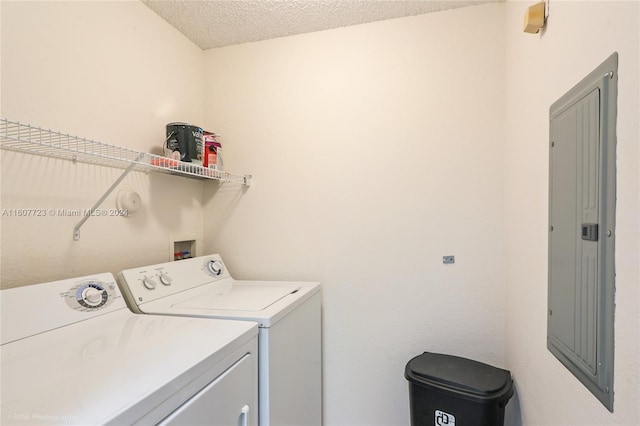 laundry room with washer and dryer, a textured ceiling, and electric panel