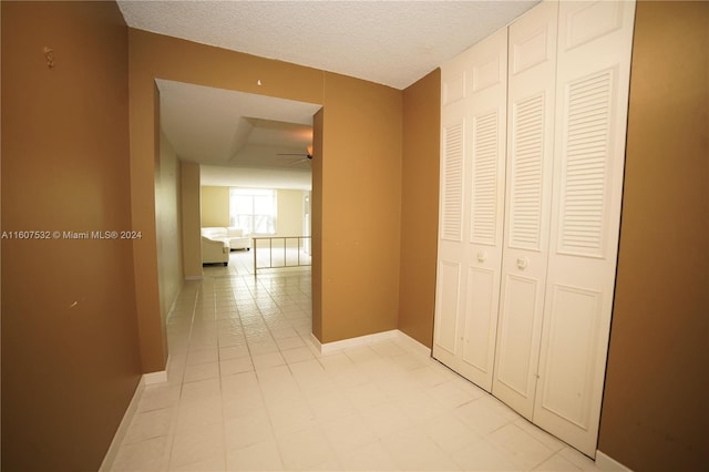 hall featuring a textured ceiling and light tile floors