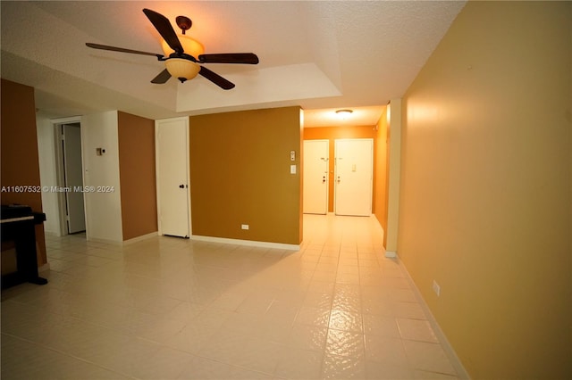 interior space featuring a raised ceiling, ceiling fan, and a textured ceiling