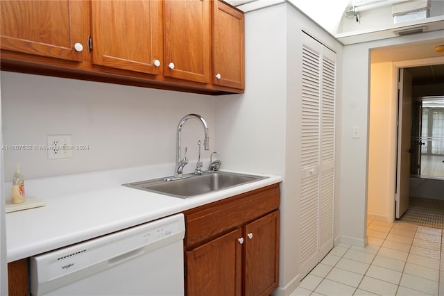 kitchen featuring white dishwasher, sink, and light tile flooring