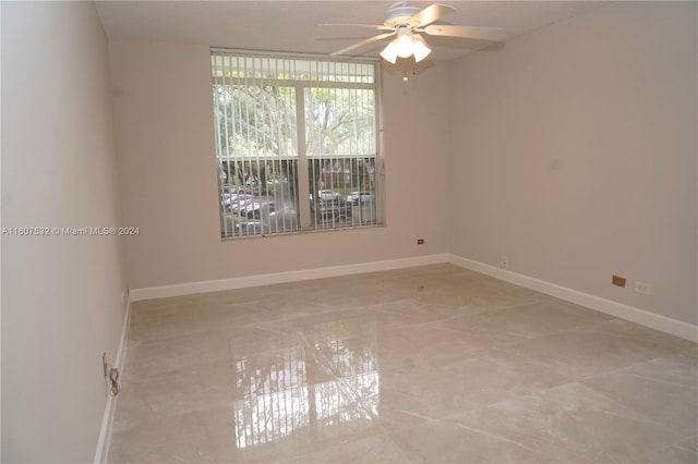 spare room featuring expansive windows, ceiling fan, and tile floors