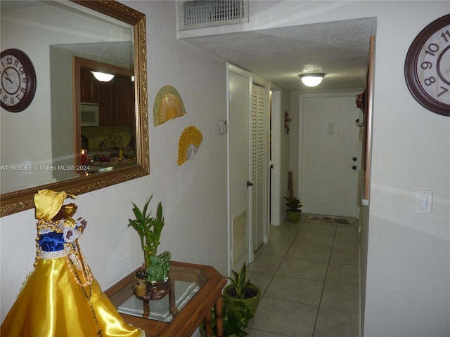 hall with tile patterned floors and a textured ceiling