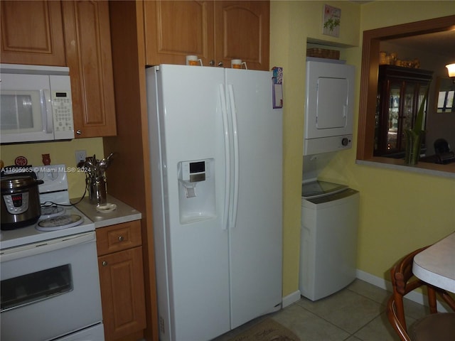 kitchen featuring white appliances, stacked washer / dryer, and light tile patterned floors