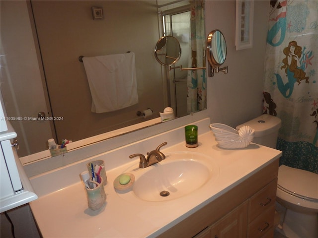 bathroom featuring a shower with shower curtain, vanity, and toilet