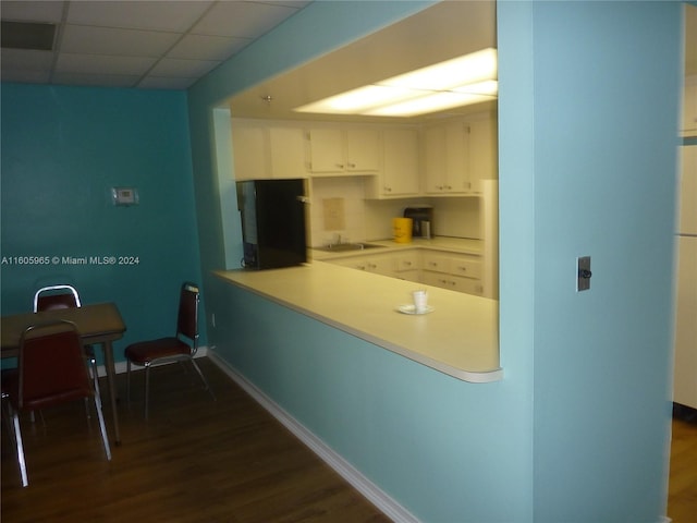 kitchen featuring white cabinetry, a drop ceiling, sink, dark wood-type flooring, and refrigerator