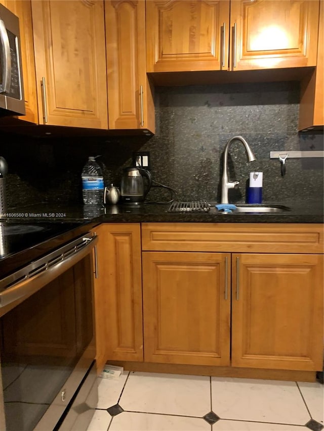 kitchen with sink, light tile floors, tasteful backsplash, and stove