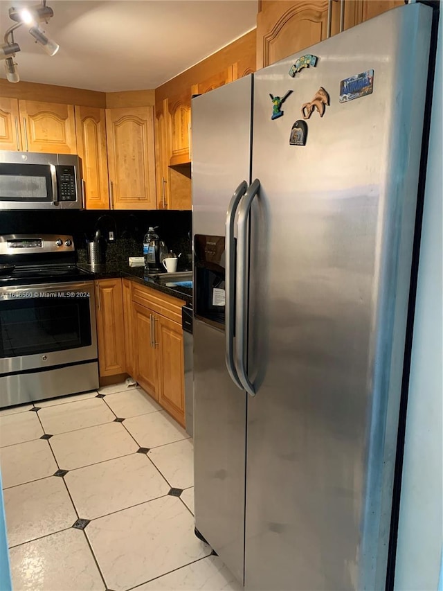 kitchen featuring track lighting, appliances with stainless steel finishes, tasteful backsplash, and light tile floors