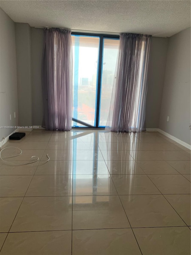 tiled empty room featuring plenty of natural light and a textured ceiling