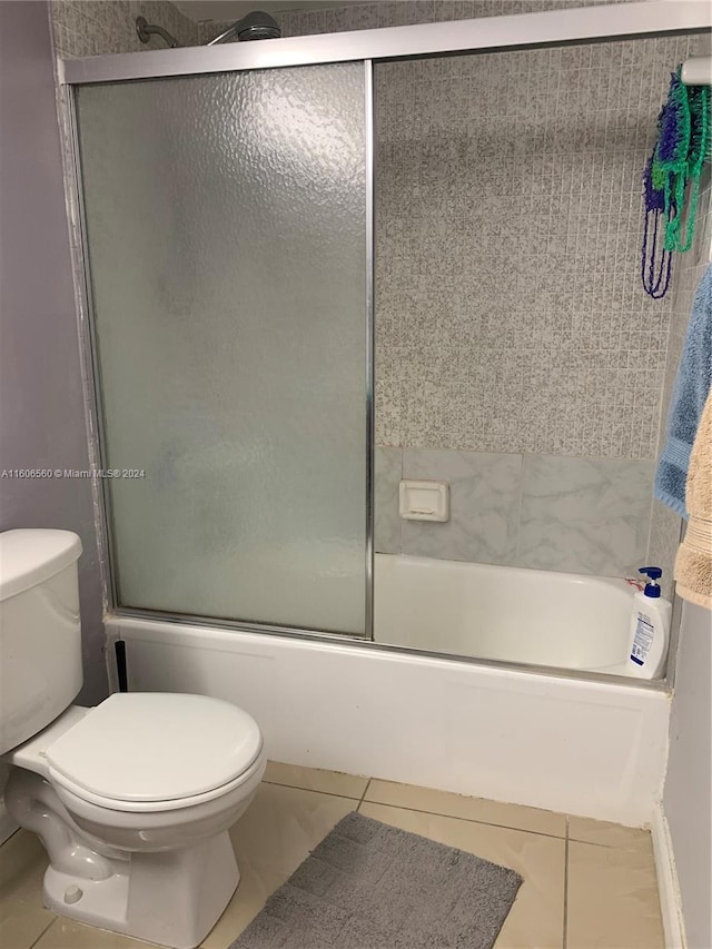 bathroom with tile flooring, enclosed tub / shower combo, and toilet