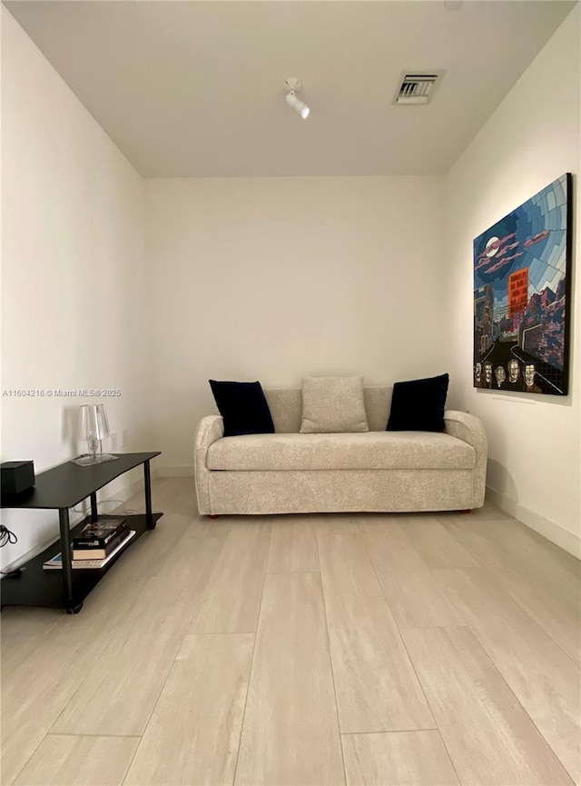 living area with baseboards, visible vents, and wood finished floors