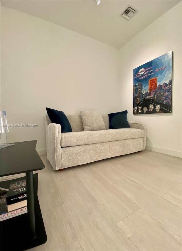 living area featuring baseboards, visible vents, and wood finished floors