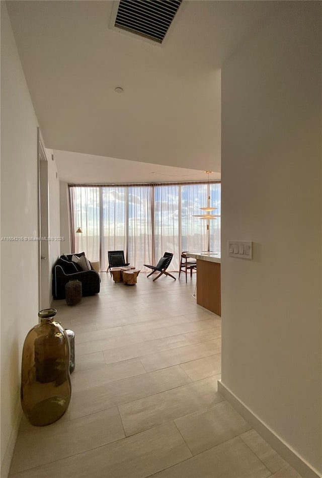 hall featuring plenty of natural light, visible vents, and baseboards