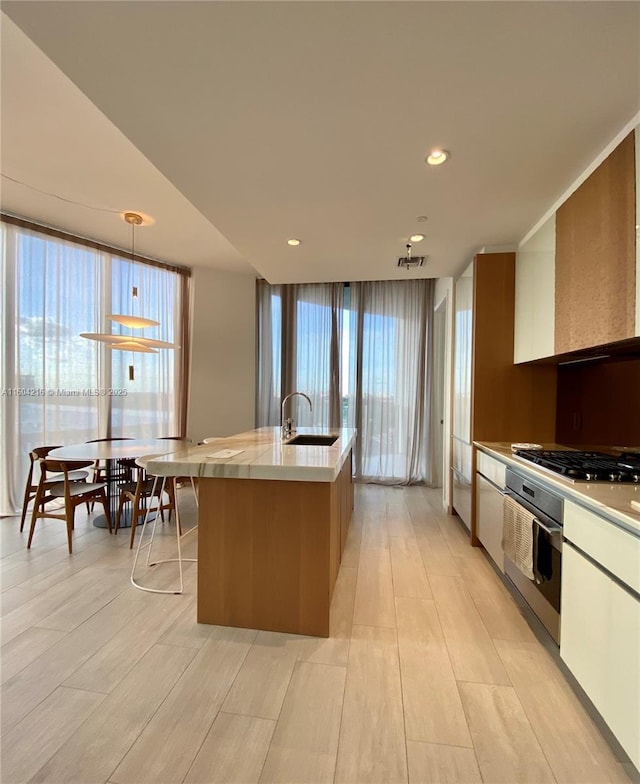 kitchen with recessed lighting, a sink, light countertops, appliances with stainless steel finishes, and hanging light fixtures