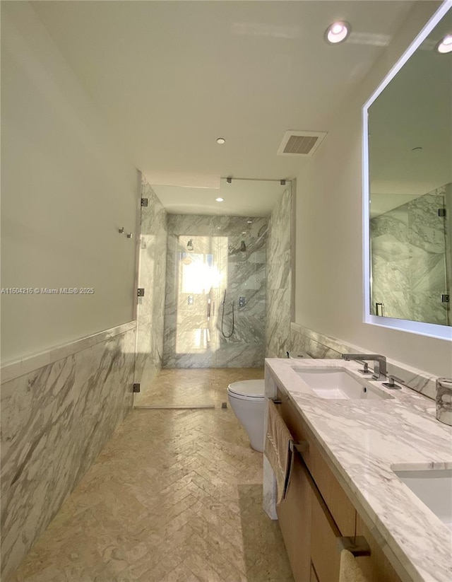 bathroom featuring double vanity, tile walls, visible vents, and a sink