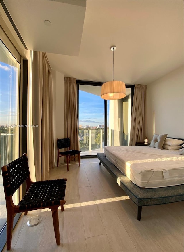 bedroom with a wall of windows and wood finished floors