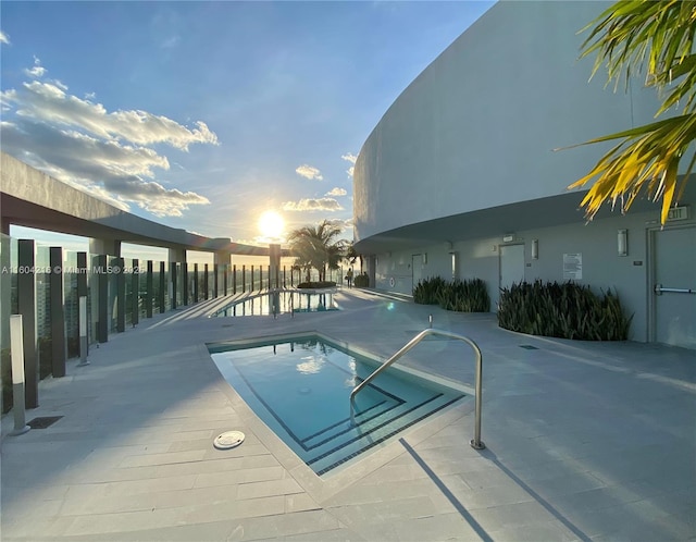 pool at dusk featuring a patio area