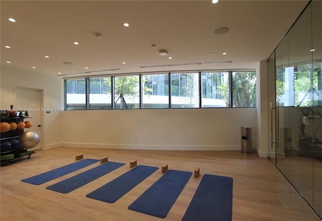 workout room with a wealth of natural light, baseboards, light wood finished floors, and recessed lighting