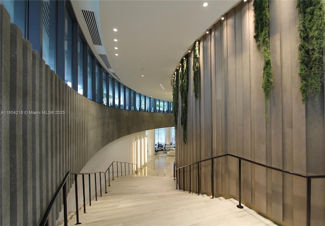 stairway featuring a towering ceiling, a wall of windows, wood finished floors, and recessed lighting