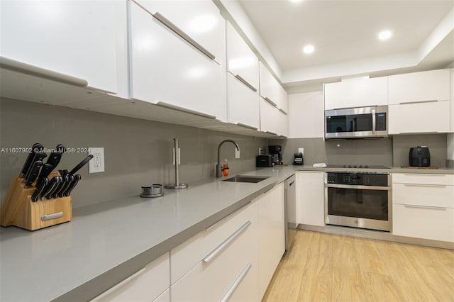 kitchen featuring white cabinets, sink, stainless steel appliances, and light hardwood / wood-style flooring