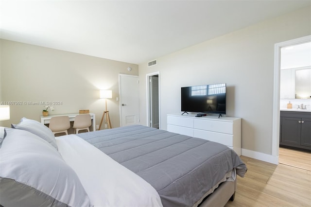 bedroom featuring light wood-type flooring, sink, and ensuite bath