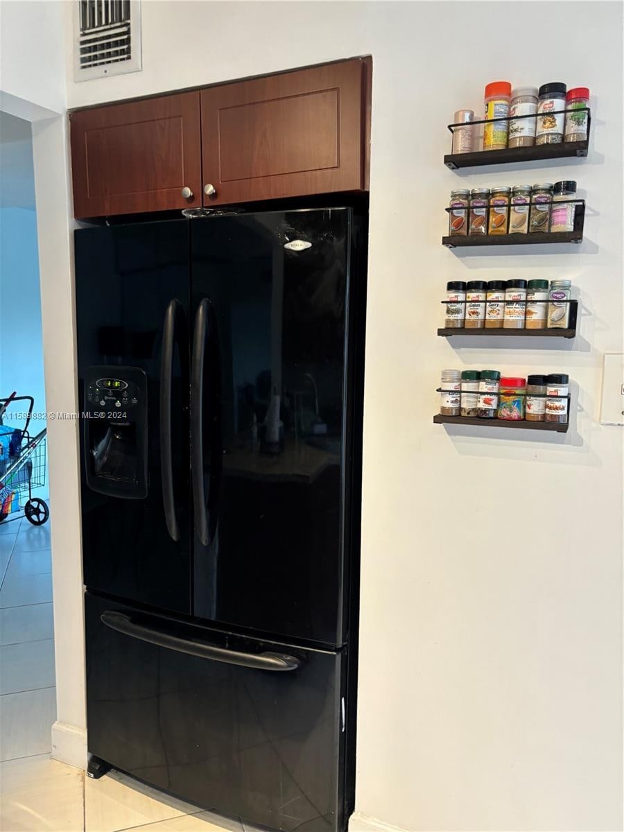 interior space featuring black refrigerator with ice dispenser and light tile patterned flooring