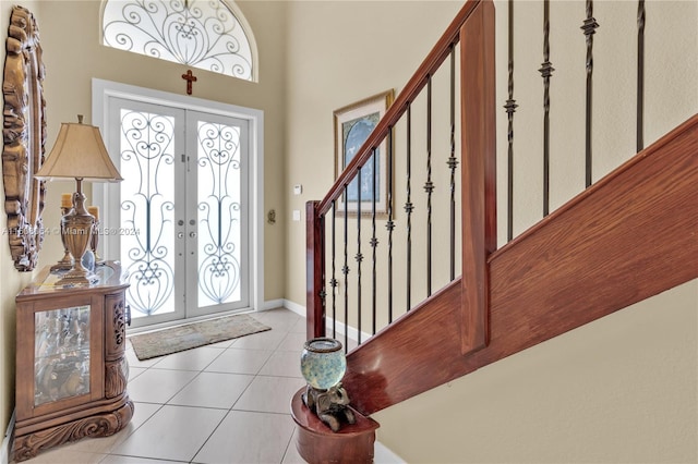 foyer entrance with light tile patterned floors, baseboards, stairway, and french doors
