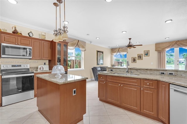 kitchen featuring a kitchen island, a sink, ornamental molding, appliances with stainless steel finishes, and brown cabinets